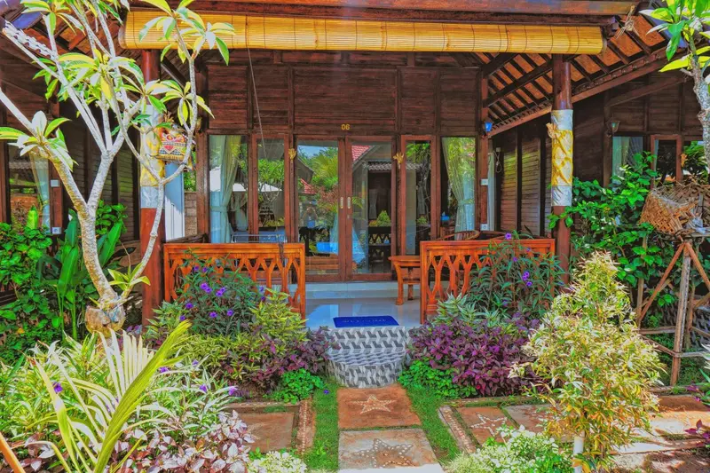 Entree d'un bungalow en bois avec vegetation tropicale.