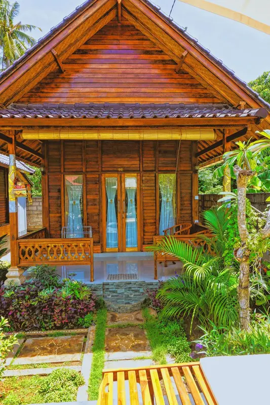 Petite maison en bois avec une terrasse et une végétation luxuriante.