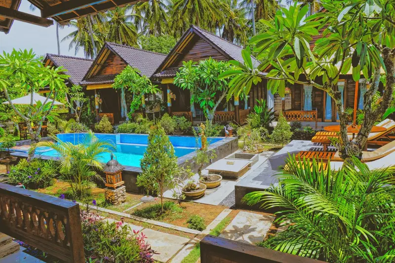 Une piscine bordée de végétation luxuriante devant des bungalows en bois.