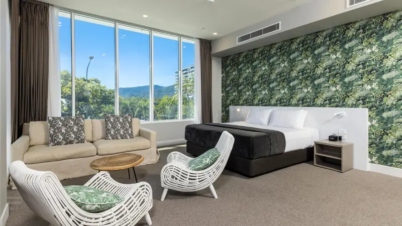 Une chambre lumineuse avec un canapé, des fauteuils et un grand lit.