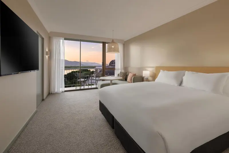 Chambre lumineuse avec un grand lit et une vue sur un paysage montagneux.