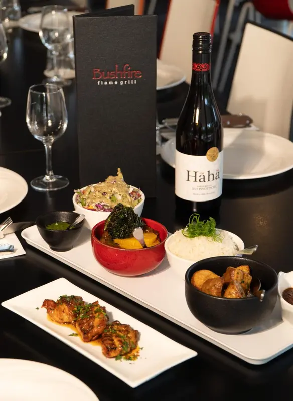 Une table est dressée avec des plats variés, une bouteille de vin et des couverts.