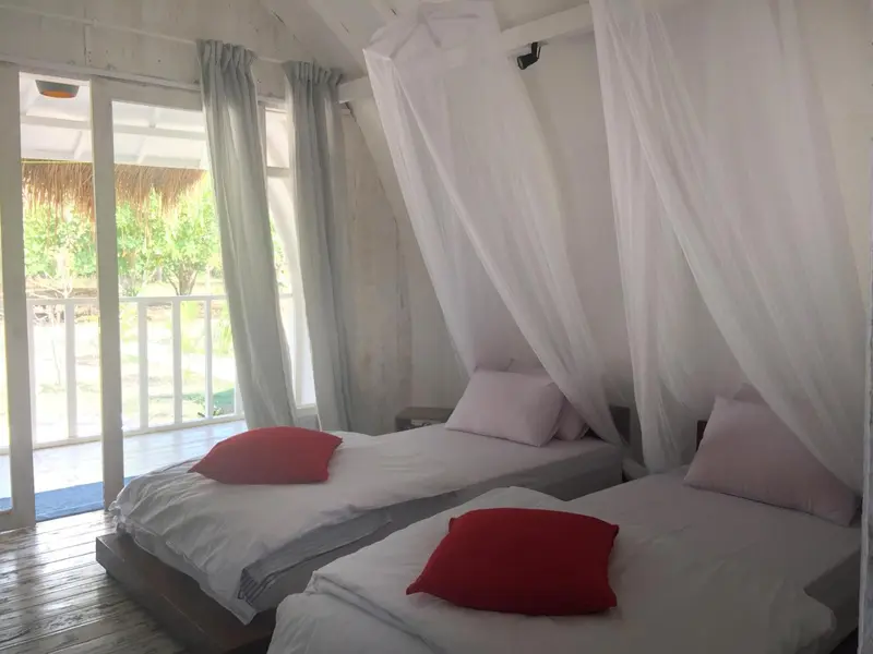 Une chambre lumineuse avec deux lits simples et une terrasse.