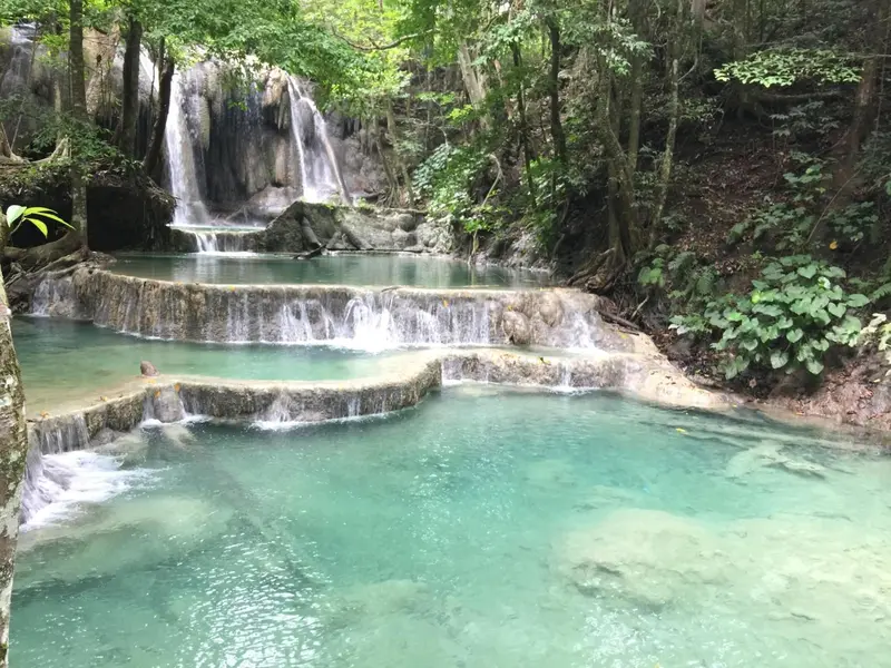 Cascade turquoise s'écoulant en terrasses dans une végétation luxuriante.