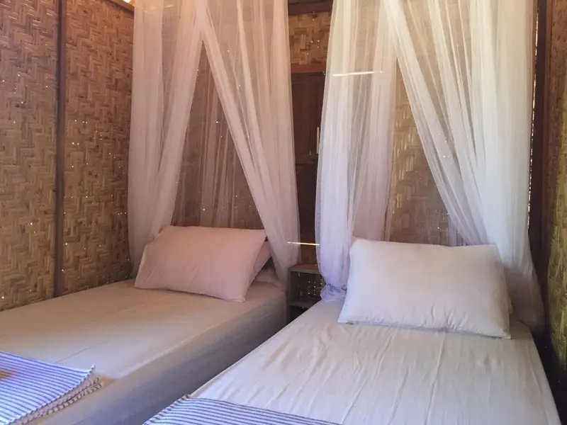 Deux lits simples dans une chambre aux murs en bambou.
