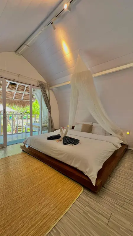 Une chambre lumineuse avec un grand lit à baldaquin et une vue sur l'extérieur.
