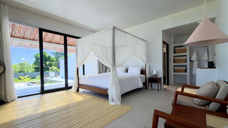Une chambre lumineuse avec un lit à baldaquin et un coin salon.