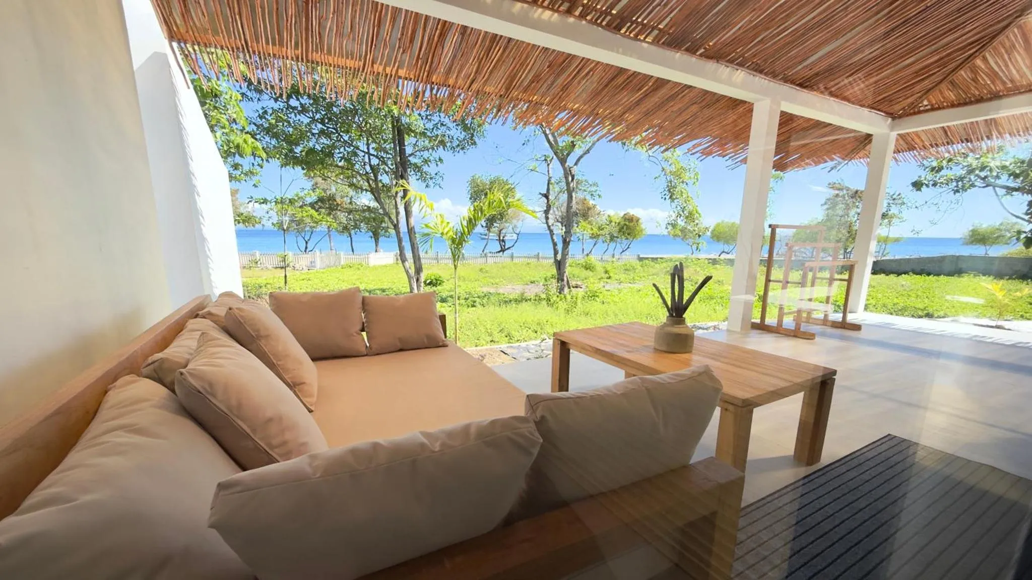 Espace de détente extérieur avec canapés et vue sur la mer.