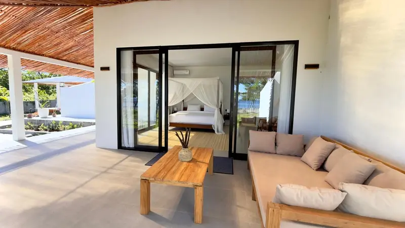Espace de détente extérieur avec canapé et table basse devant une chambre.