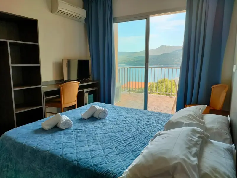 Une chambre lumineuse avec un lit fait et une vue sur la mer.