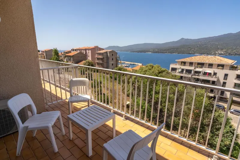 Terrasse carrelée avec mobilier blanc donnant sur une vue panoramique.