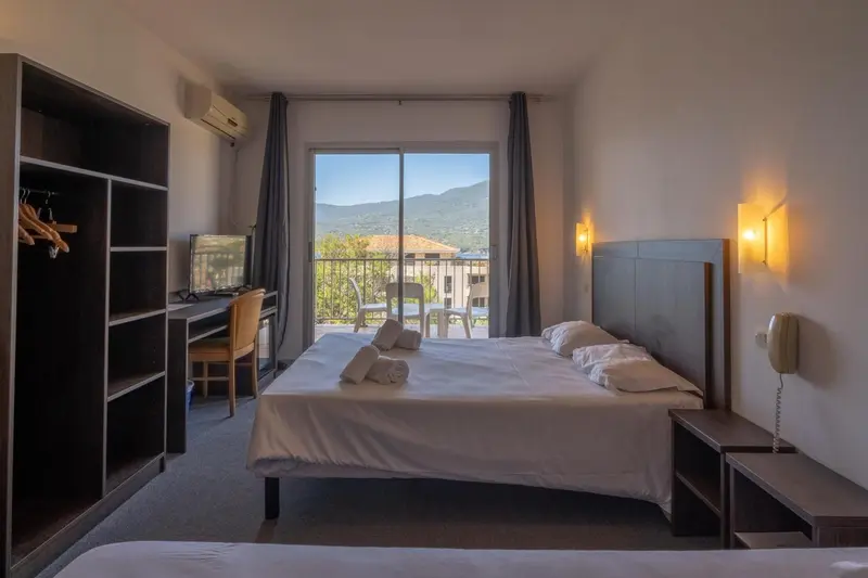 Chambre lumineuse avec un grand lit et vue sur les montagnes.