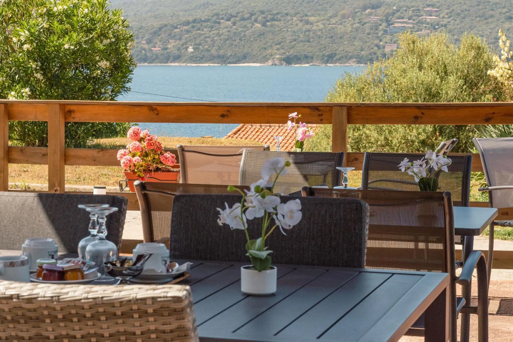 Une table est dressée sur une terrasse avec une vue sur la mer.