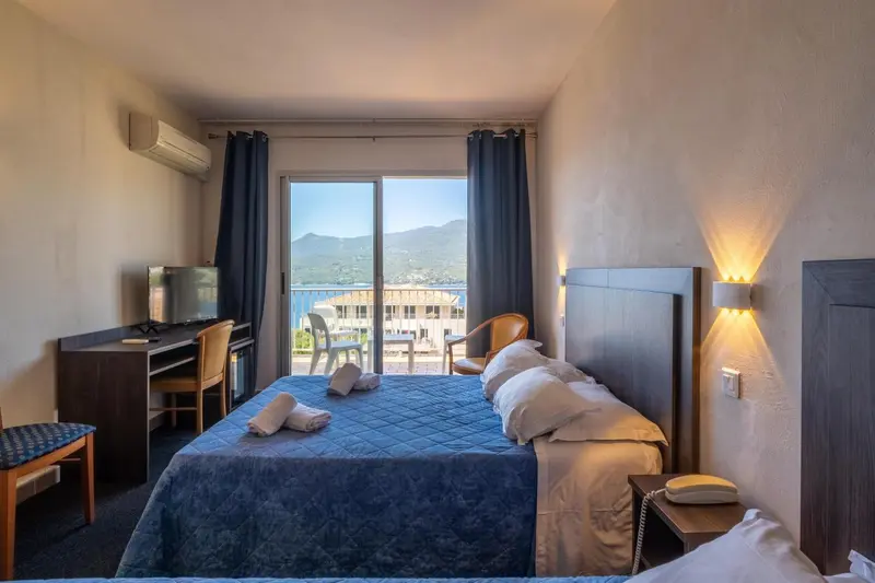 Chambre lumineuse avec un lit double donnant sur une vue dégagée.