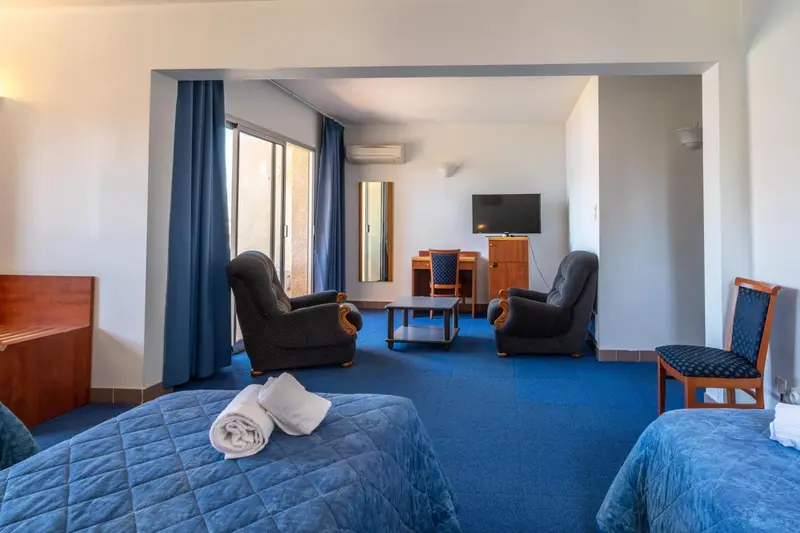 Espace de séjour lumineux avec canapés et télévision à écran plat.