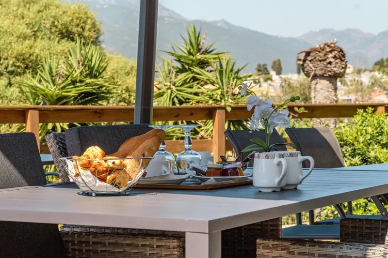 Une table est dressée avec des viennoiseries, des fruits et des boissons.