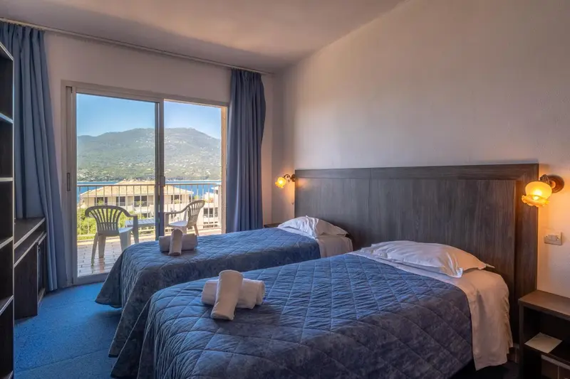 Chambre avec deux lits simples donnant sur une vue dégagée.