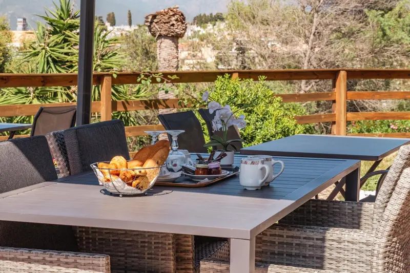Une table est dressée pour le petit-déjeuner sur une terrasse ensoleillée.