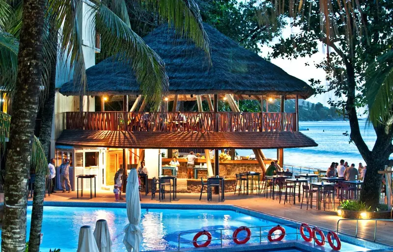 Un bar en bord de mer avec une piscine au premier plan.