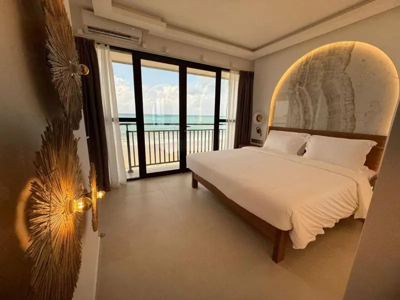 Chambre lumineuse avec un grand lit face à la mer.