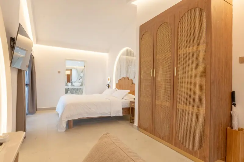 Une chambre lumineuse avec un grand lit et une armoire en bois.