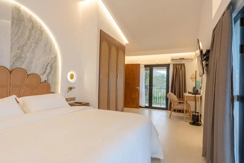 Chambre lumineuse avec un grand lit et un accès à une terrasse.