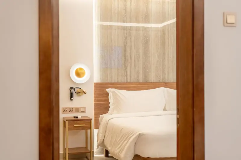 Une chambre lumineuse avec un lit blanc et des meubles en bois.