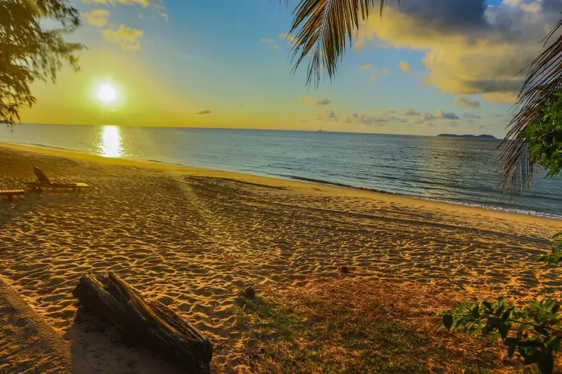 Une plage de sable doré baignée par le soleil couchant.