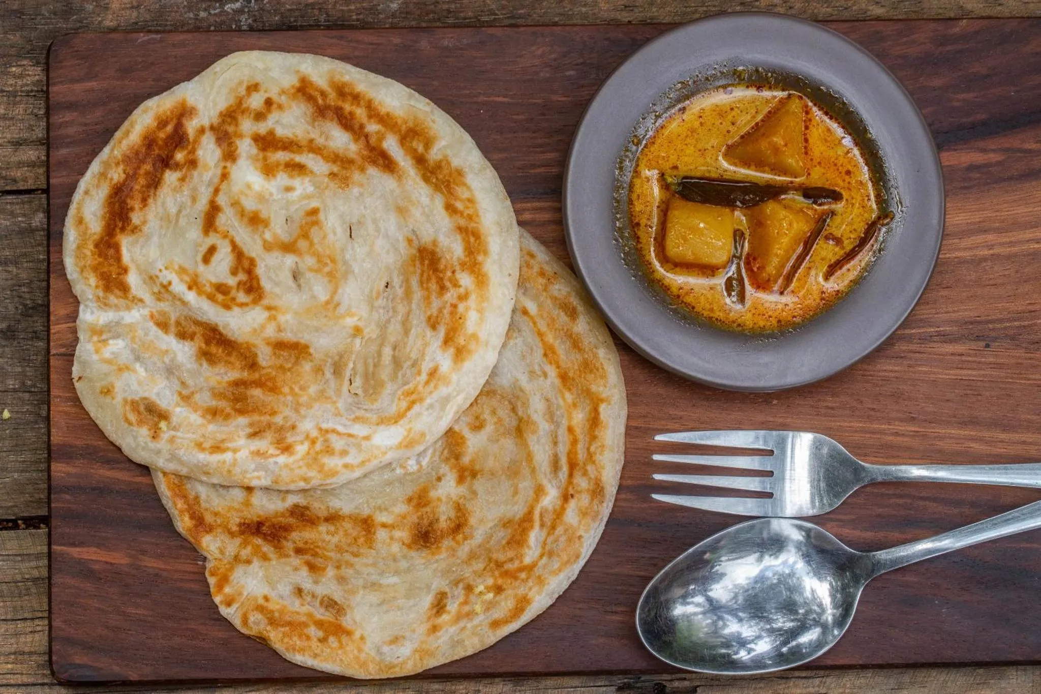 Assiette de galettes dorées accompagnées d'une sauce et de couverts.