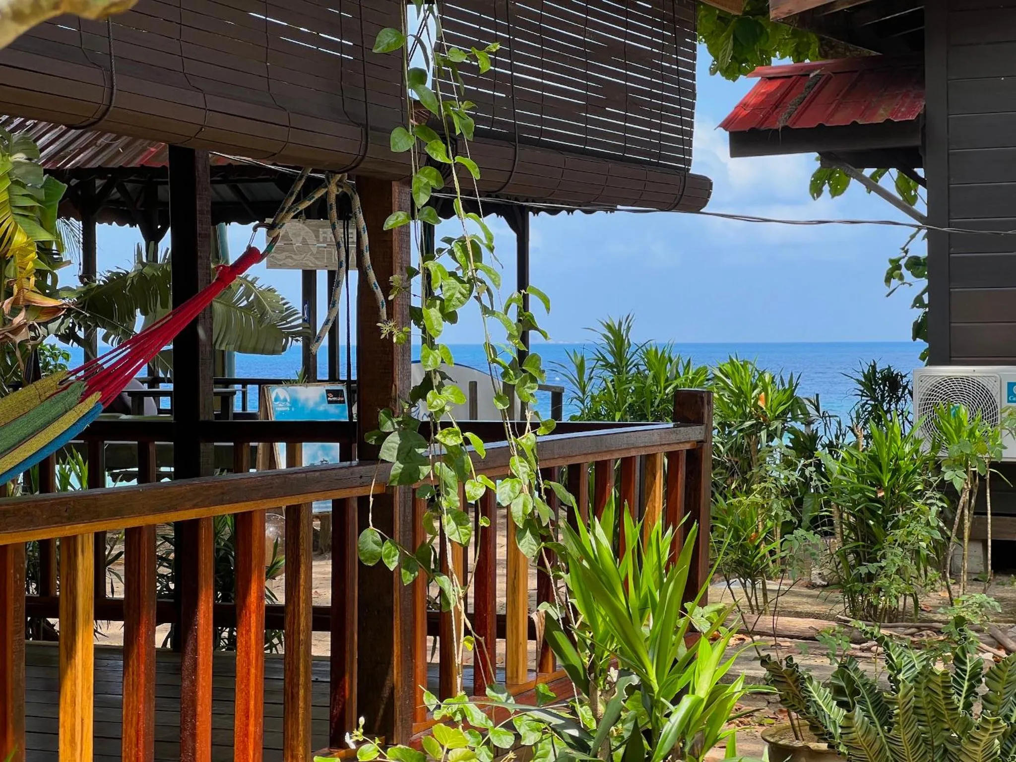 Terrasse en bois avec hamac donnant sur la mer.