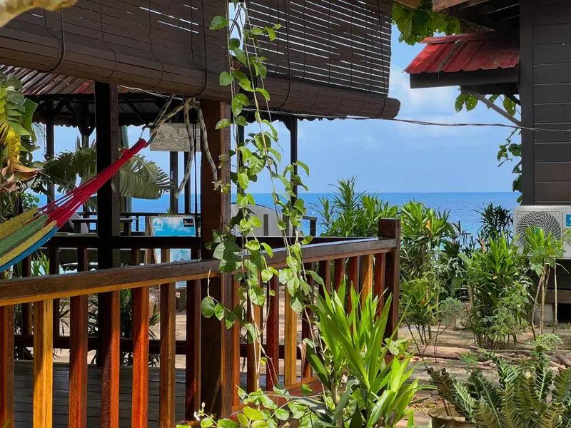 Terrasse en bois avec hamac donnant sur la mer.