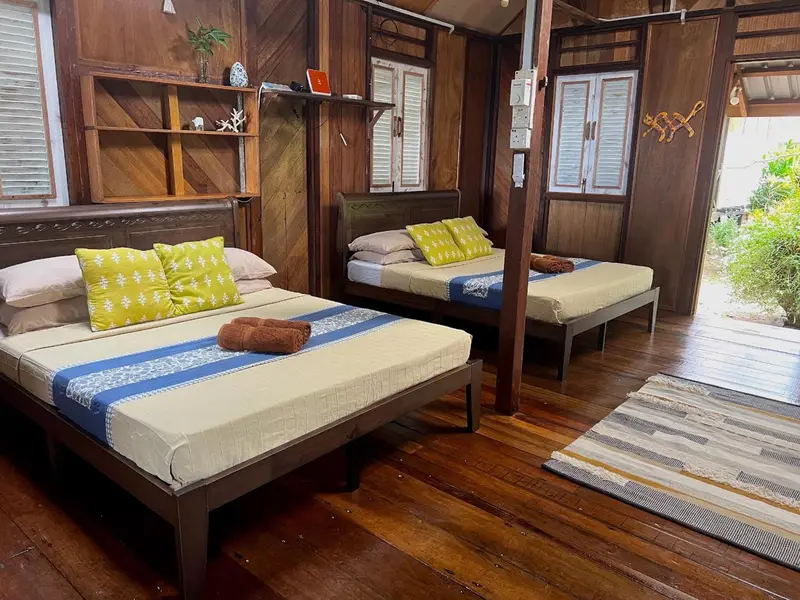 Deux lits simples avec couvertures colorées dans une chambre en bois.