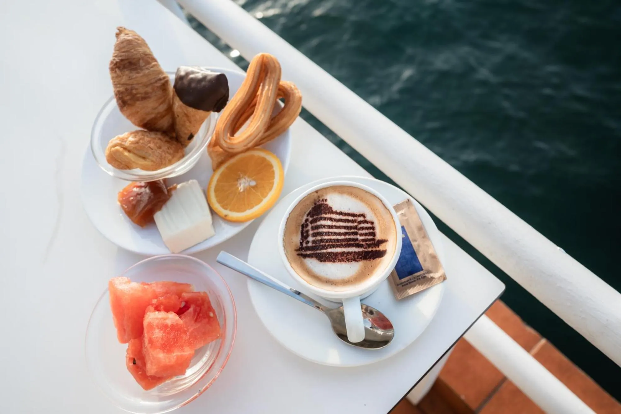 Assiette de pâtisseries, de fruits et une tasse de café décorée.