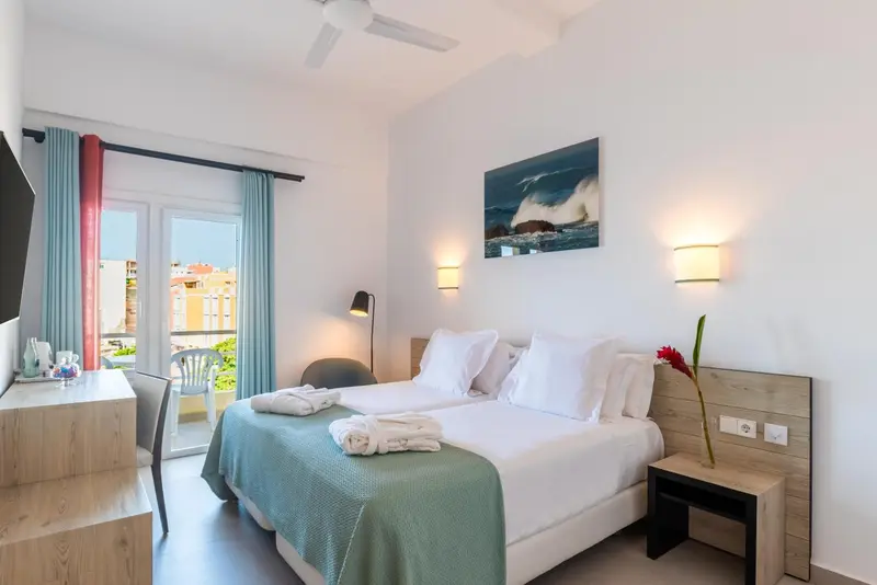 Chambre lumineuse avec un lit double et une vue sur l'extérieur.