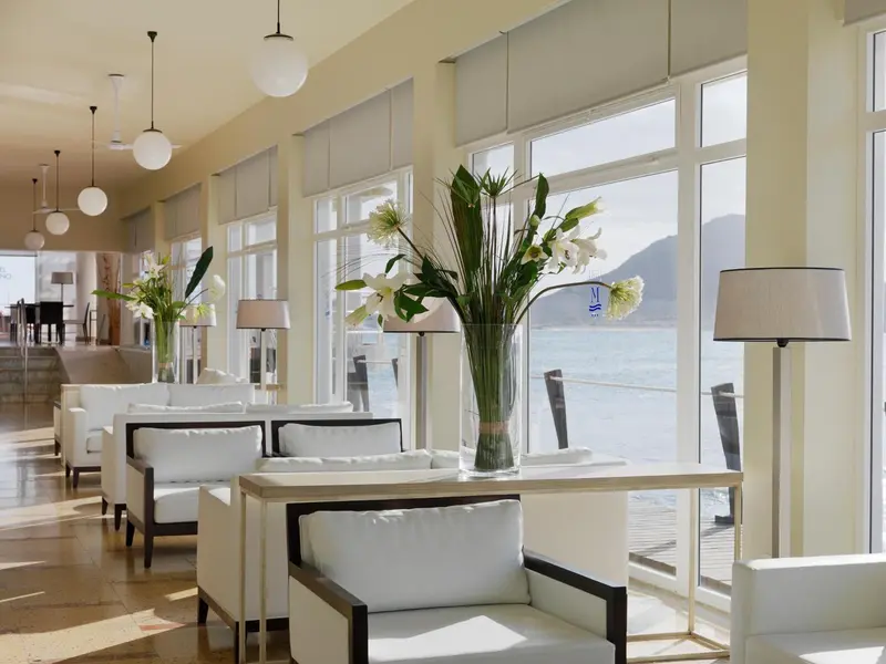 Espace de détente lumineux avec mobilier blanc et vue sur la mer.