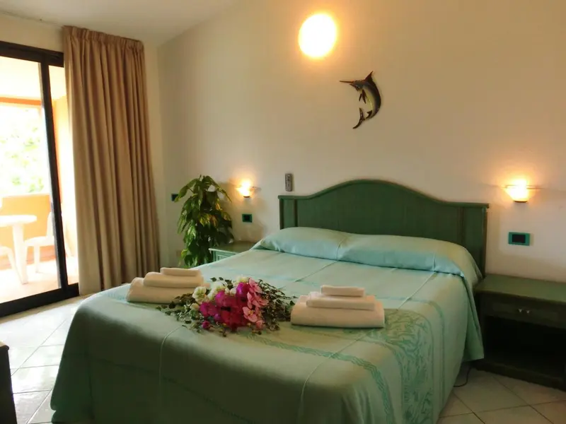 Une chambre lumineuse avec un grand lit décoré de fleurs et une baie vitrée.