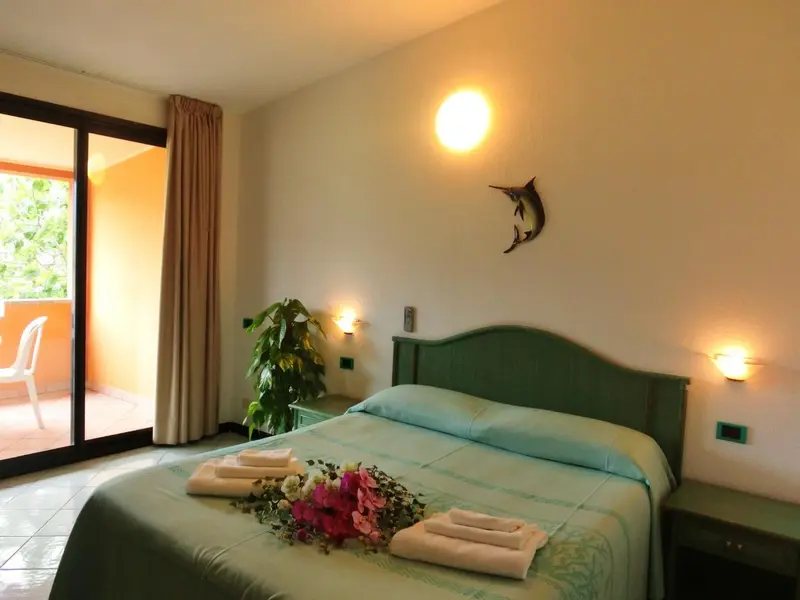 Une chambre lumineuse avec un lit décoré de fleurs et un accès à une terrasse.
