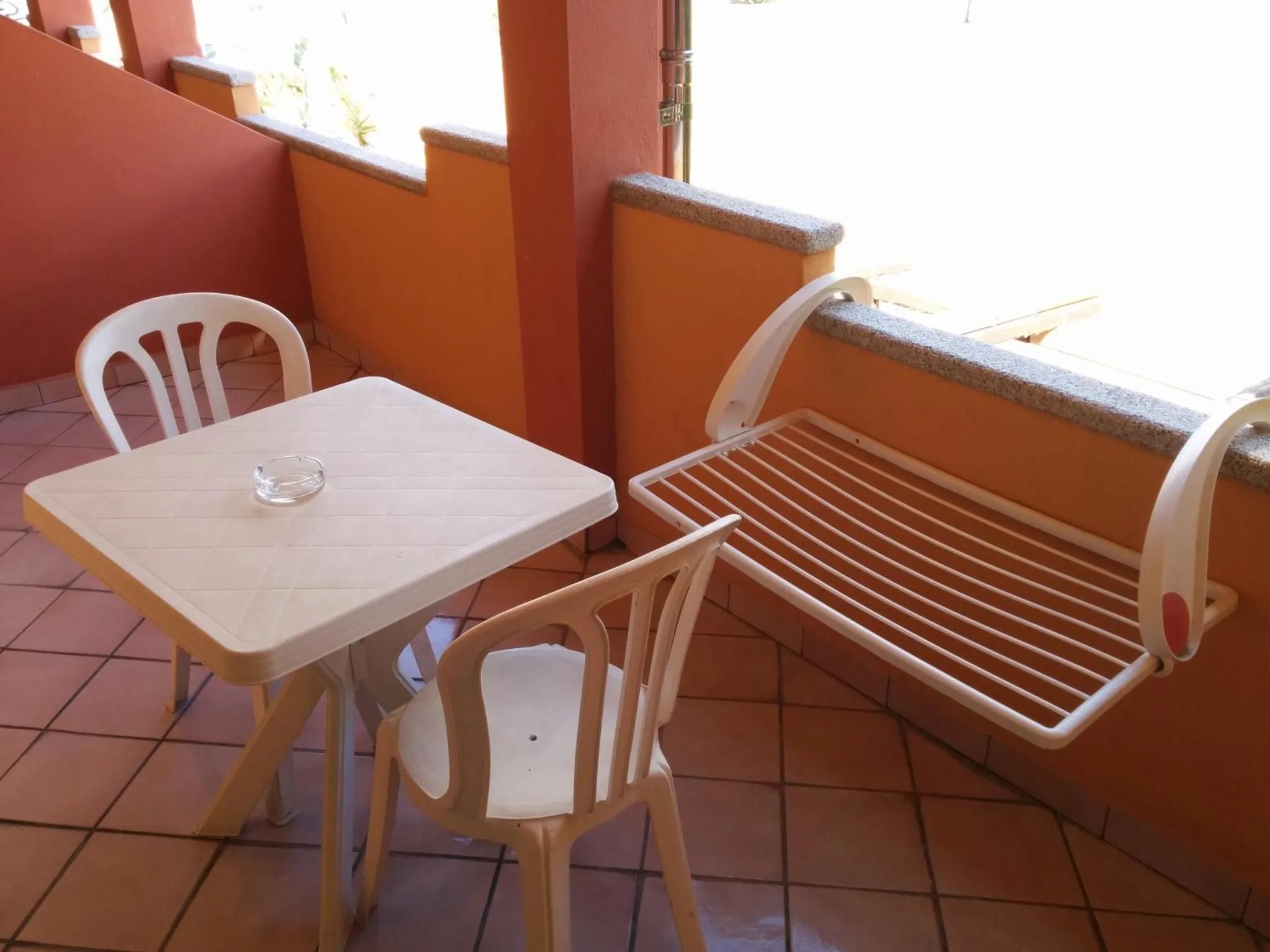 Une table et des chaises en plastique sur une terrasse carree.
