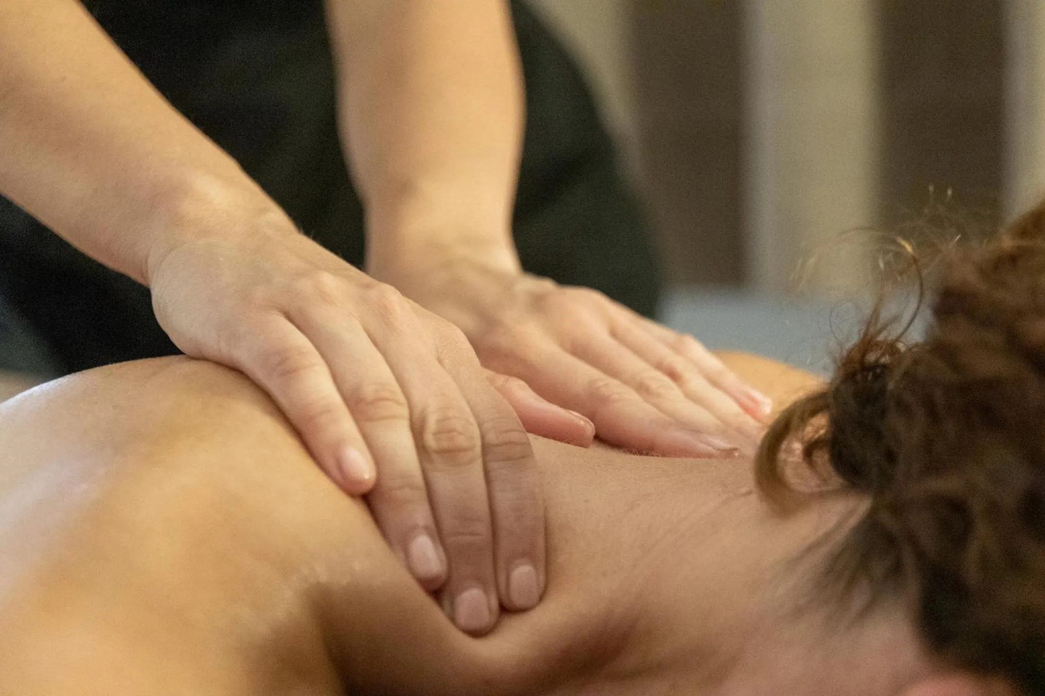 Mains effectuant un massage sur le dos d'une personne allongée.