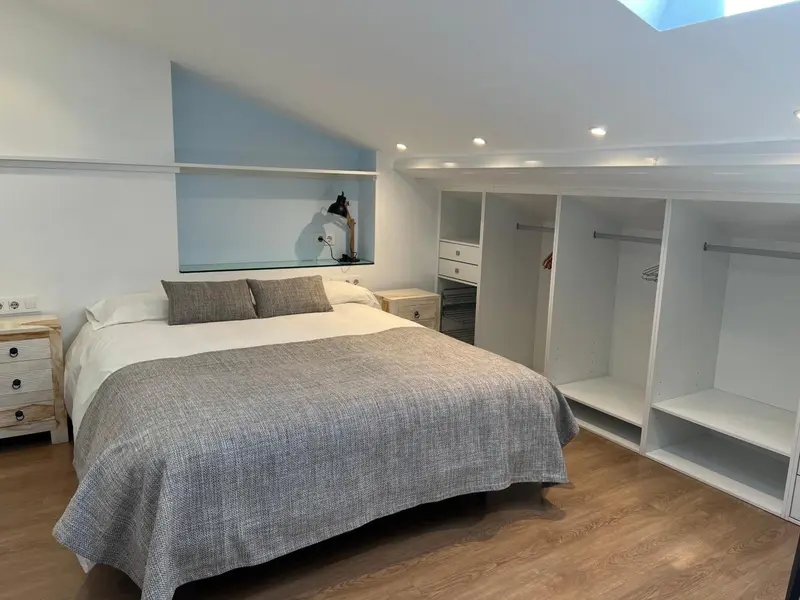 Une chambre lumineuse avec un lit double et des rangements intégrés.