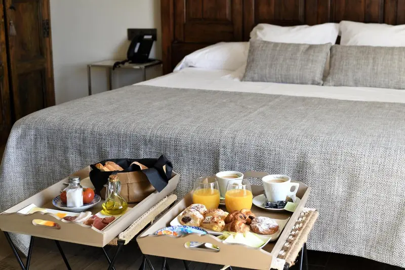 Un petit-déjeuner est servi sur un plateau devant un lit fait dans une chambre.
