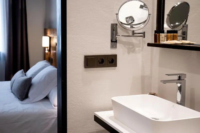 Une salle de bain moderne avec un lavabo blanc et un miroir rond.
