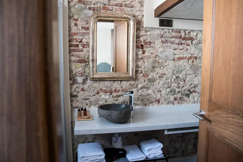 Une salle de bain avec un lavabo en pierre et un mur en briques apparentes.