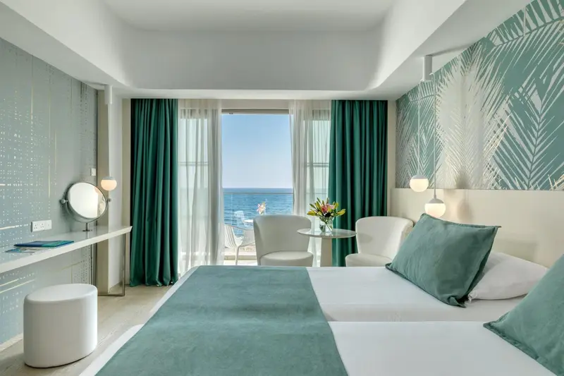 Chambre lumineuse avec vue sur la mer et balcon.