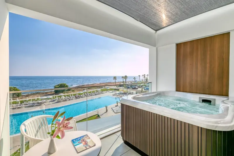 Une terrasse avec un jacuzzi offre une vue sur la mer et une piscine.
