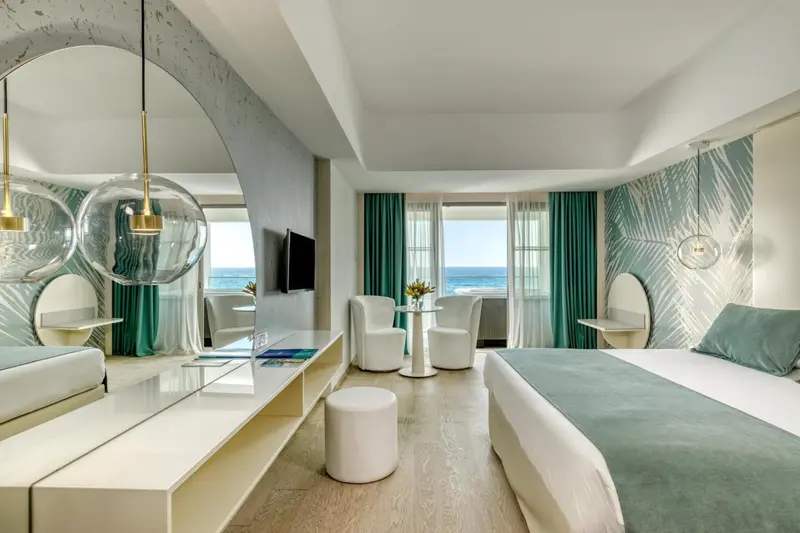 Chambre lumineuse avec un lit confortable et une vue sur la mer.