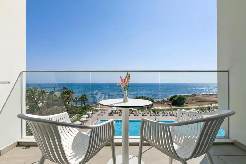 Terrasse avec mobilier blanc donnant sur une piscine et la mer.