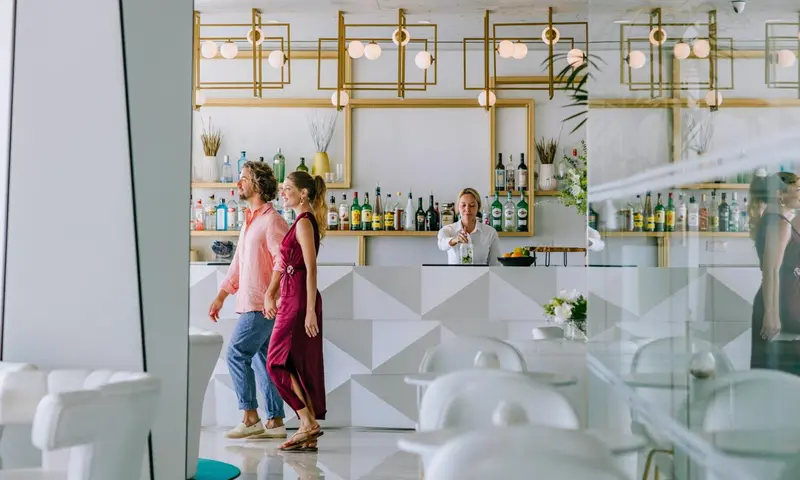 Un bar lumineux avec un comptoir blanc et des clients.