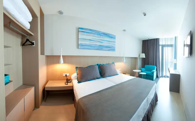 Une chambre lumineuse avec un grand lit et un coin salon.
