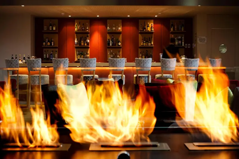 Un comptoir de bar illuminé par des flammes dans une ambiance chaleureuse.